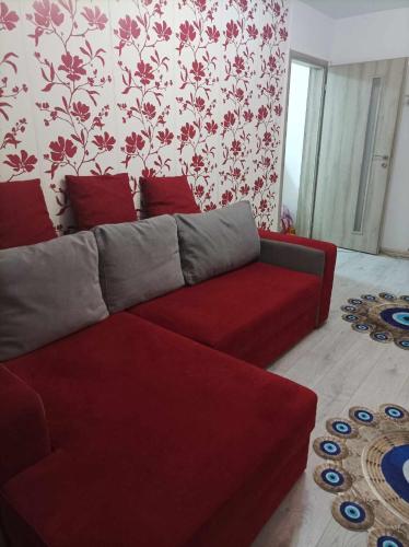 a living room with a red couch and floral wallpaper at Apartament amy in Mangalia