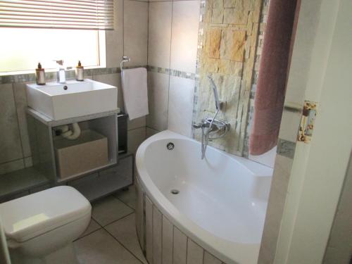 La salle de bains est pourvue d'une baignoire, d'un lavabo et de toilettes. dans l'établissement home from home, à Krugersdorp