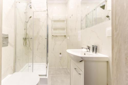 a white bathroom with a shower and a sink at Nadmorski Apartament V by Holiday&Sun in Grzybowo