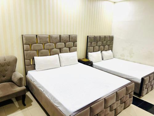 um quarto com 2 camas e uma cadeira em Oriole Luxury Hotel em Islamabad