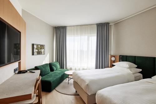 a hotel room with two beds and a green couch at Georg Ots Spa Hotel in Kuressaare