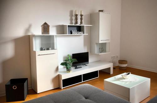 Biały salon z telewizorem i kanapą w obiekcie Schneiders Ferienwohnungen w mieście Braunshausen