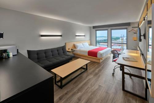 Habitación de hotel con cama y sofá en City Express Plus by Marriott Leon Centro de Convenciones en León