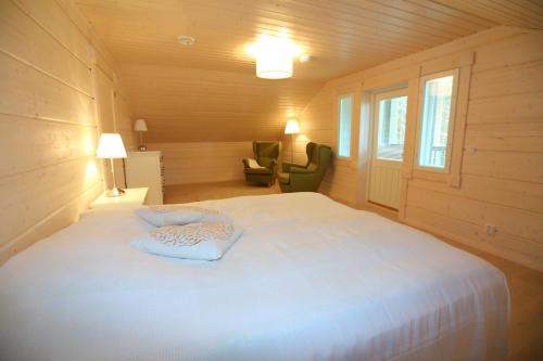 ein Schlafzimmer mit einem großen weißen Bett und einem Stuhl in der Unterkunft Villa Tukkilahti 4 in Savonranta