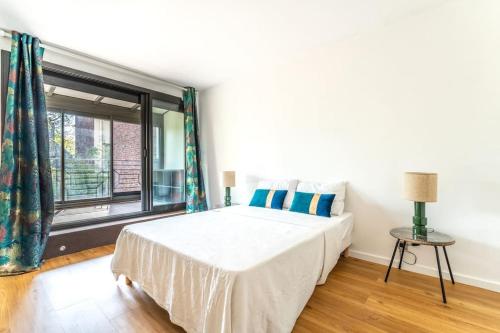 1 dormitorio con cama y ventana grande en Spacieuse Maison à 15 min de la Tour Eiffel, en Suresnes