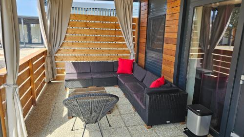 a couch on a balcony with red pillows at CHARTA mobile home Roko in Pirovac