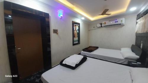 2 camas en una habitación pequeña con puerta en Galaxy Inn, en Khurda
