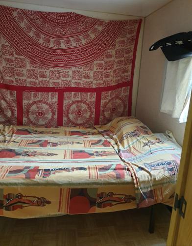 Ce lit se trouve dans une chambre dotée d'un mur rouge. dans l'établissement Mobil home chez un particulier pour 1 à 4 personnes à 800 m de la plage de Valras pas dans un camping, à Sérignan