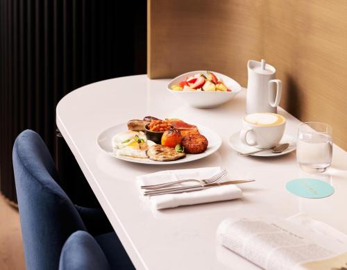 a table with a plate of food and a cup of coffee at Hyatt House London Stratford - Aparthotel in London