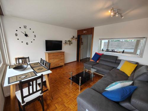 a living room with a couch and a clock on the wall at 2 bedroom Apartment at Bahnhofcity in Feldkirch