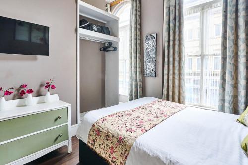 a bedroom with a bed with a dresser and a window at Satori Serviced Apartments in Manchester