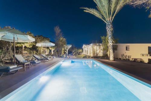 a swimming pool with chairs and palm trees at night at MyThea Villa by "elite" in Lithakia