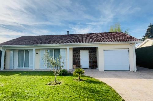 een huis met twee garagedeuren in een tuin bij Villa Bonheur sur Marne Near Disneyland in Claye-Souilly