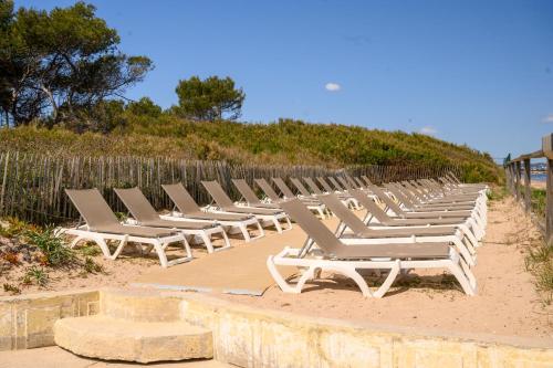 a row of white lounge chairs on a beach at Le studio de giens in Hyères