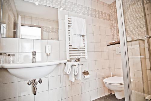 a white bathroom with a sink and a toilet at ParkHotel Fulda in Fulda