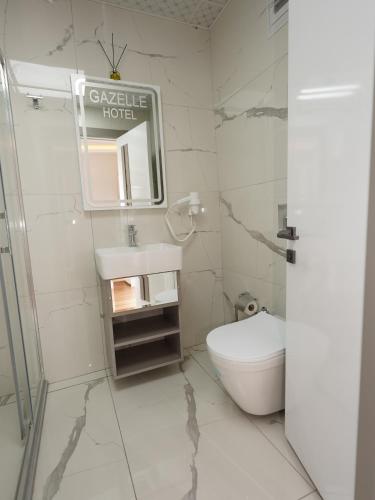 a white bathroom with a toilet and a mirror at gazelle suites in Istanbul