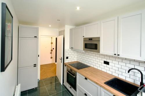 a kitchen with white cabinets and a sink at Parisian style apartment in Maisons-Alfort
