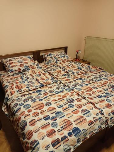 Una cama con un edredón encima. en Apartmani Jelena, en Vrnjačka Banja