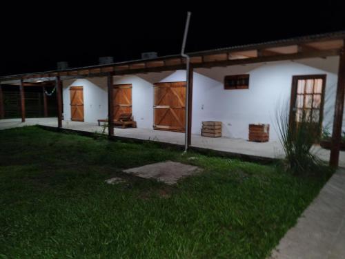 uma casa branca com portas de madeira e um jardim de relva em La Blanca em Mercedes