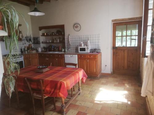 une cuisine avec une table recouverte d'une nappe dans l'établissement Gîte de la glycine, à Marmande