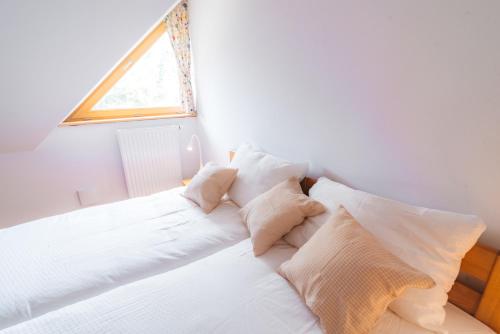 a bedroom with a white bed with pillows and a window at Rogla Alpina Residence in Zreče
