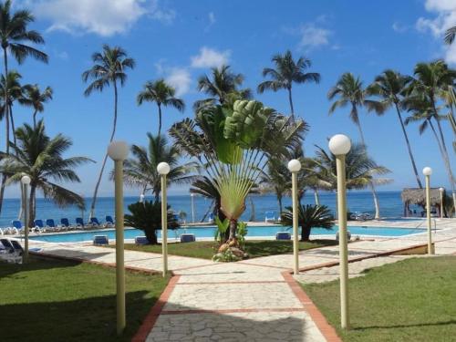 un complexe avec une piscine, des palmiers et l'océan dans l'établissement Appartamento Mustique Juan Dolio fronte mare, à Juan Pedro