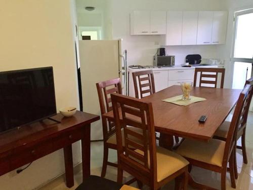 Il comprend une cuisine avec une table en bois, des chaises et une télévision. dans l'établissement Appartamento Mustique Juan Dolio fronte mare, à Juan Pedro