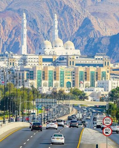 a large building with white domes and cars on a highway at Dar Al Amara in Muscat