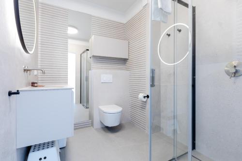 ein weißes Badezimmer mit Dusche und Toilette in der Unterkunft HEVENIA POGORZELICA - APARTAMENT 1 in Pogorzelica