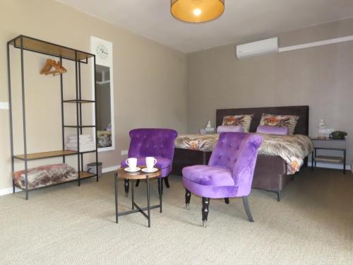 een slaapkamer met paarse stoelen en een bed en een tafel bij B & B de Pinguin in Bergentheim