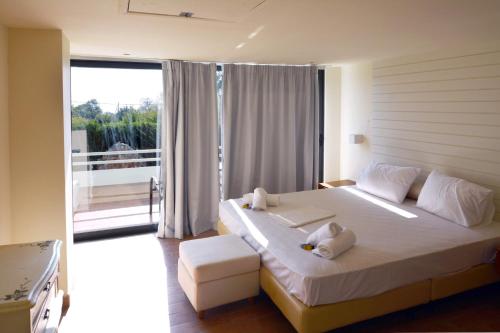 a bedroom with a large bed and a balcony at Holiday Village - Swimming pool apartments in Kamena Vourla