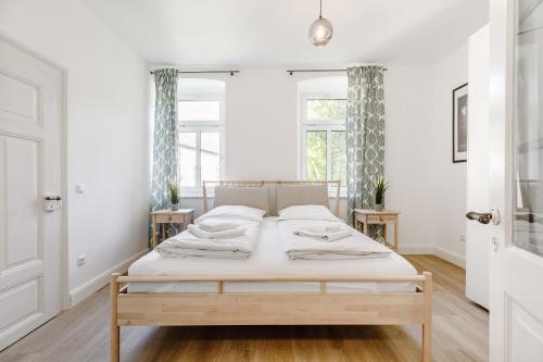 a bed in a white room with two windows at Old Town Center Apartments in Kulmbach