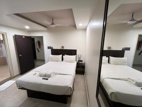 two beds in a room with a mirror at Diviyum Manor in Port Blair