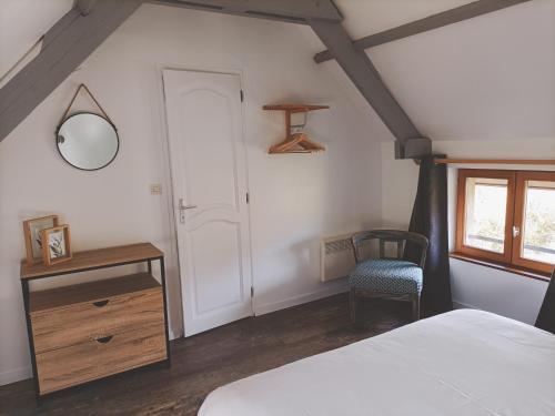 una camera da letto con un letto, uno specchio e una sedia di LE TEMPS D'UN INSTANT a Vattetot-sur-Mer