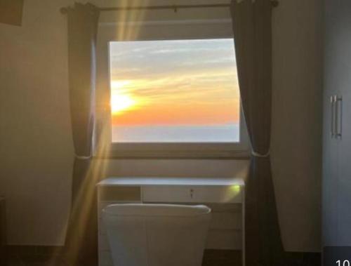 B&B La Danza del Mare في اناكابري: حمام مع نافذة فوق المرحاض مع غروب الشمس
