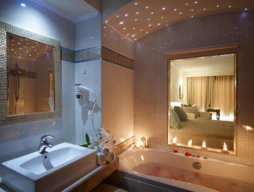 a bathroom with a tub and a large mirror at Atrium Prestige Thalasso Spa Resort & Villas in Lachania