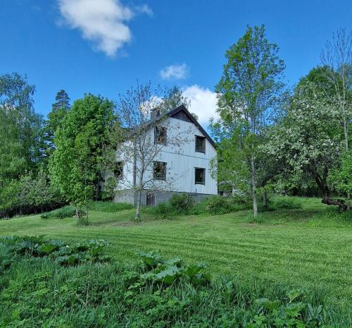 una vieja casa blanca en un campo con árboles en Remontoitu suuri hirsitalo luonnon keskellä Nurmijärvellä, en Perttula