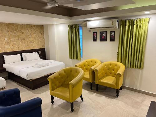 a bedroom with a bed and two yellow chairs at Diviyum Manor in Port Blair