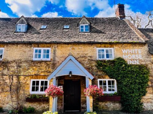 una vieja casa de piedra con un cartel que lee la posada de la Casa Blanca en The White Horse Inn en Deddington