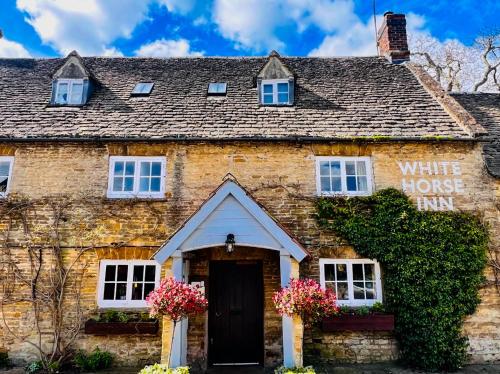 an old stone house with a sign that reads white house inn at The White Horse Inn in Deddington