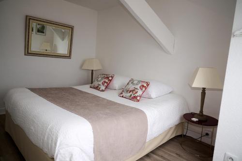 een slaapkamer met een wit bed met 2 kussens bij Les Salins de Batz-sur-mer in Batz-sur-Mer
