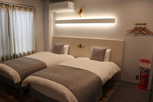 two beds in a hotel room with a large window at ホテル SHUNJU Dosse 1日1組様限定 in Kyoto