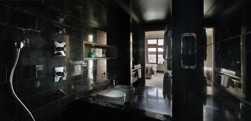 a black bathroom with a toilet and a sink at The Hari London in London