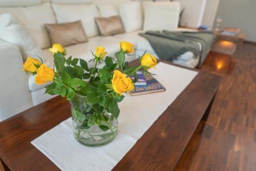 a vase with yellow flowers on a wooden table at Luxury Apartment Nana in Bled