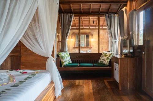 a bedroom with a bed and a window with curtains at Pondok Sebatu Eco Lodge in Tegalalang