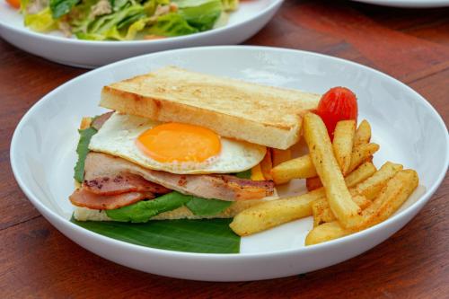 a white plate with a sandwich and french fries at PIDA COFFEE FARM LODGE in Phumĭ Pu Pal
