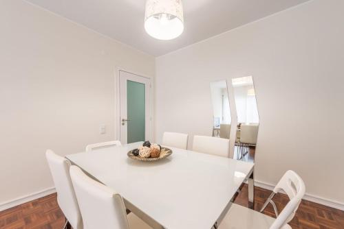 a white dining room with a white table and chairs at GuestReady - Greatful Gaia in Vila Nova de Gaia