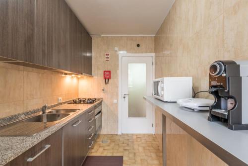 a kitchen with a sink and a microwave at GuestReady - Greatful Gaia in Vila Nova de Gaia