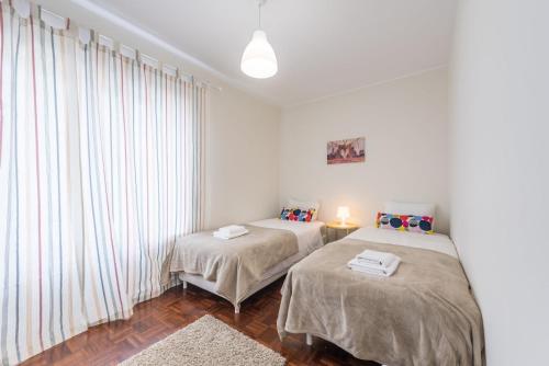 two beds in a white room with a window at GuestReady - Greatful Gaia in Vila Nova de Gaia