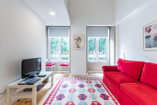 een woonkamer met een rode bank en een tv bij GuestReady - Belas Artes Duplex in Porto